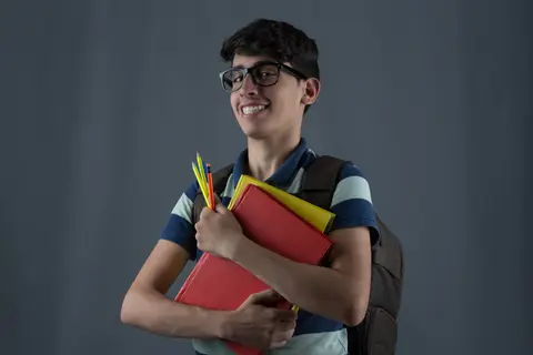طالب يحمل كتبه ويبتسم